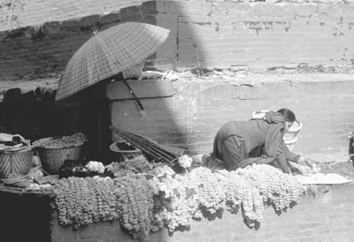 A woman sells strings of marigolds at the base of a 17th-century temple in Kathmandu’s Durbar Square.