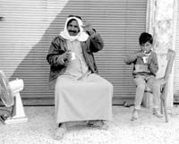 A father with his son sitting in front of a store in Deir ez-Zor, Syria.