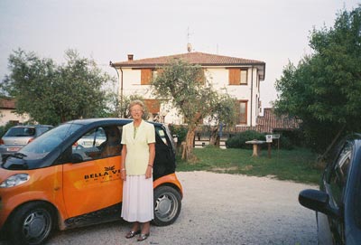 Kathleen poses beside the Residence run-about car in the parking area alongside the pool.