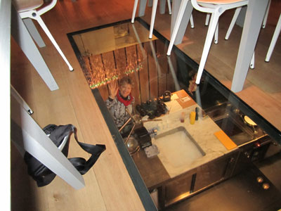 Judith Martin waving from Eat Me’s glass-ceilinged basement kitchen — Amsterdam. Photo: Ure