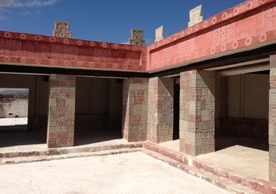 Porticoed court of the Quetzalpapalotl Palace at Teotihuacán featuring merlons and pillars decorated with carvings.