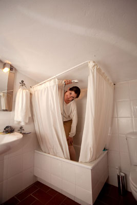 Wielding a handheld shower in a tight shower space lacking a soap dish or shelf may lead to some bathroom gymnastics. Photo by Dominic Bonuccelli