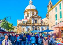 An open-air market with the Baroque backdrop of the Church of Saint Francis Xavier — Palermo, Sicily, Italy.