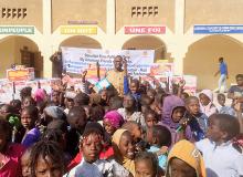 Standing behind the children is Sane, founder of ADCS, along with boxes of biscuits.