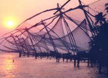 Sun going down behind seven huge, cantilevered fishing nets in the island of Vypin.