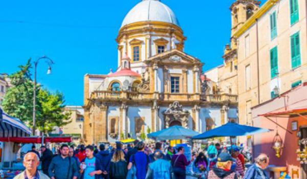 An open-air market with the Baroque backdrop of the Church of Saint Francis Xavier — Palermo, Sicily, Italy.