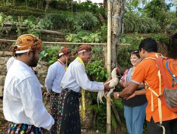 Donna Altes, representing her OAT tour group, is handed a squirming chicken by a village chief.