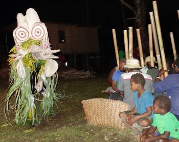 Onlookers watch a masked performer during a Baining fire dance.