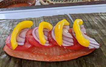 Peppers, onions and tomatoes placed on the fish.